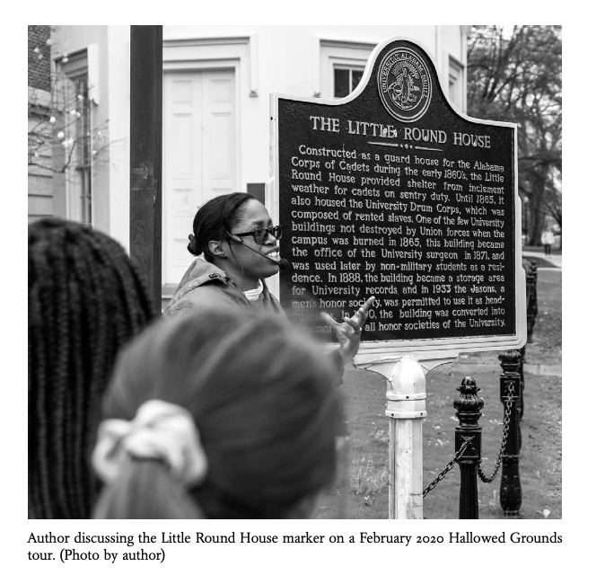 Women in front of a The Little Round House sign with caption "Author discussing the Little Round House marker on a February 2020 Hallowed Grounds tour. (Photo by author)"