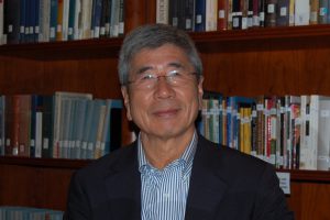 Tsuyoshi Hasegawa in front of bookcase filled with books