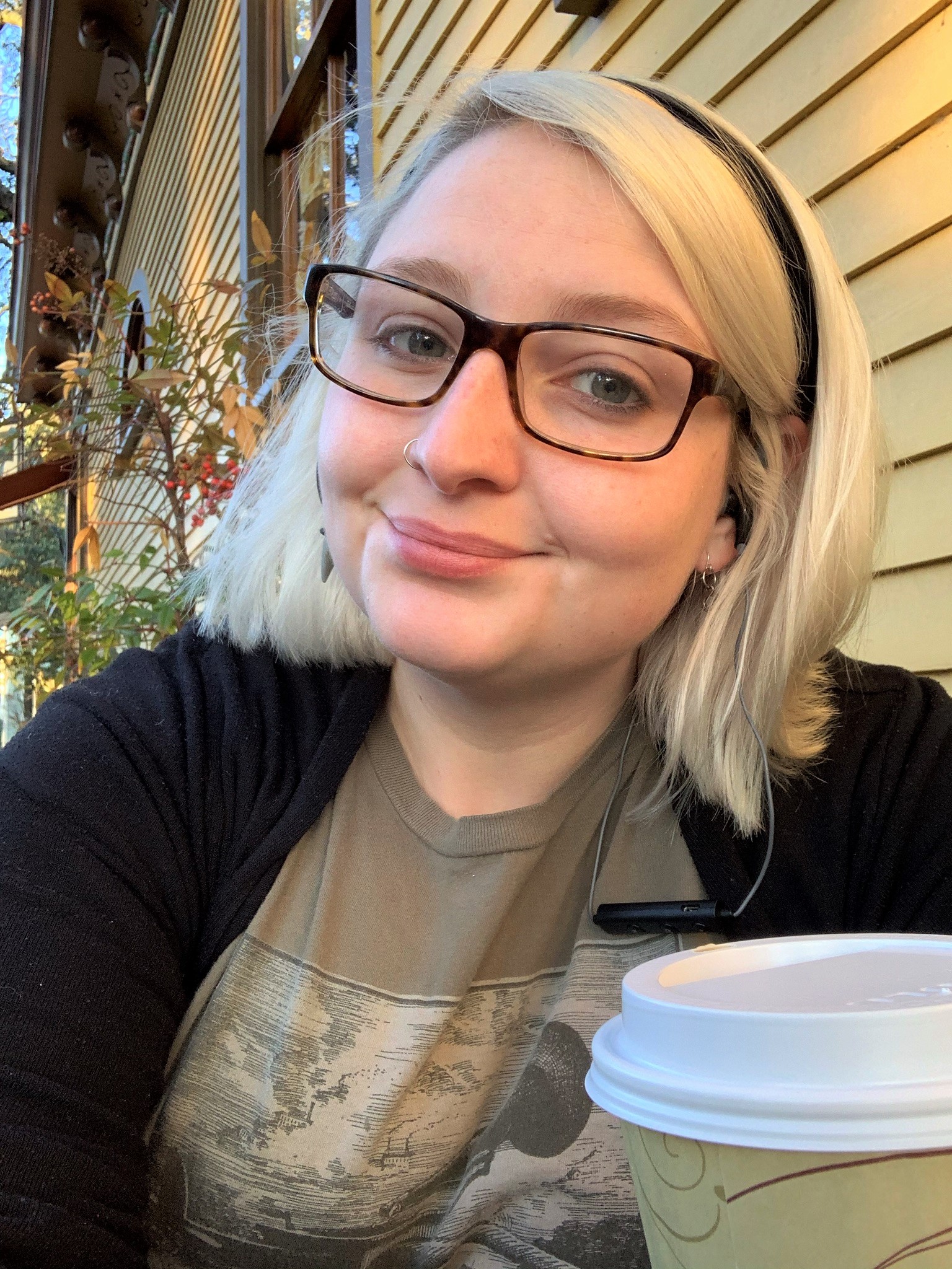 Shannon Dade sits with a cup of coffee in front of a yellow building