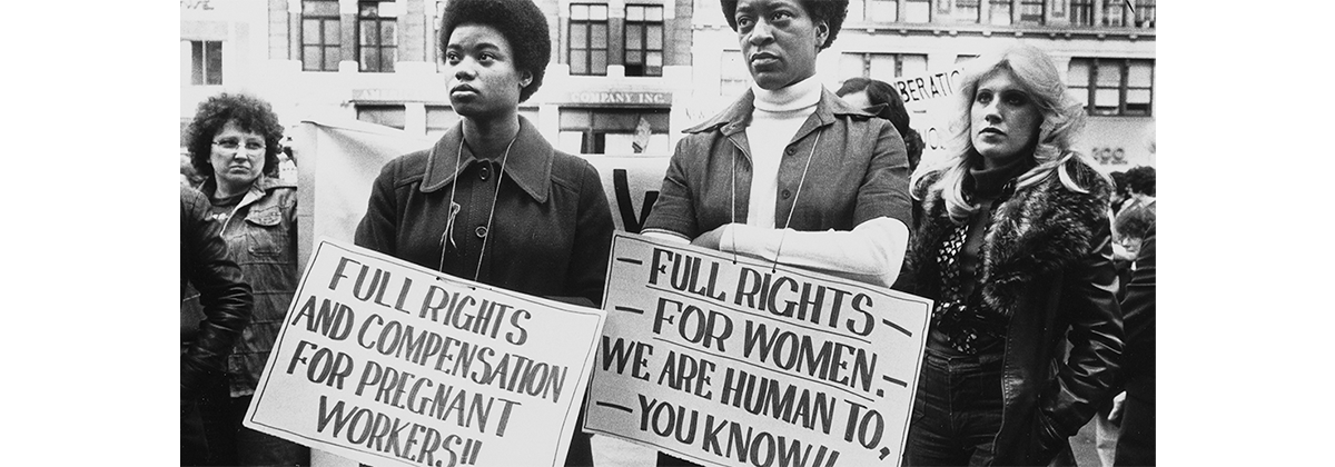 Image of four women, two with signs that read "Full rights and compensation for pregnant workers!!" and another says "Full rights for women. We are human to, you know!!"