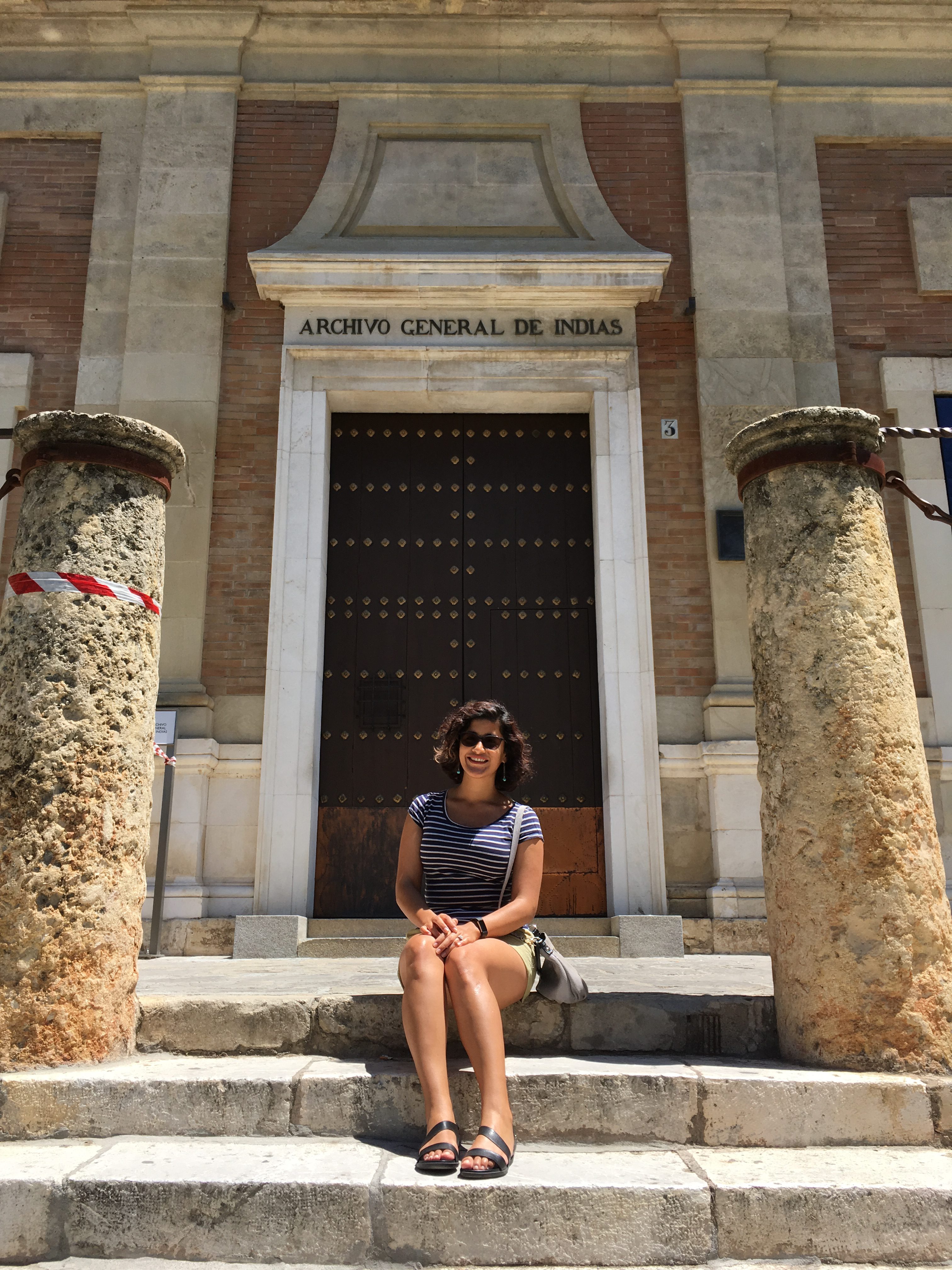 Andreina Soto sitting on the steps of Archivo General De Indias